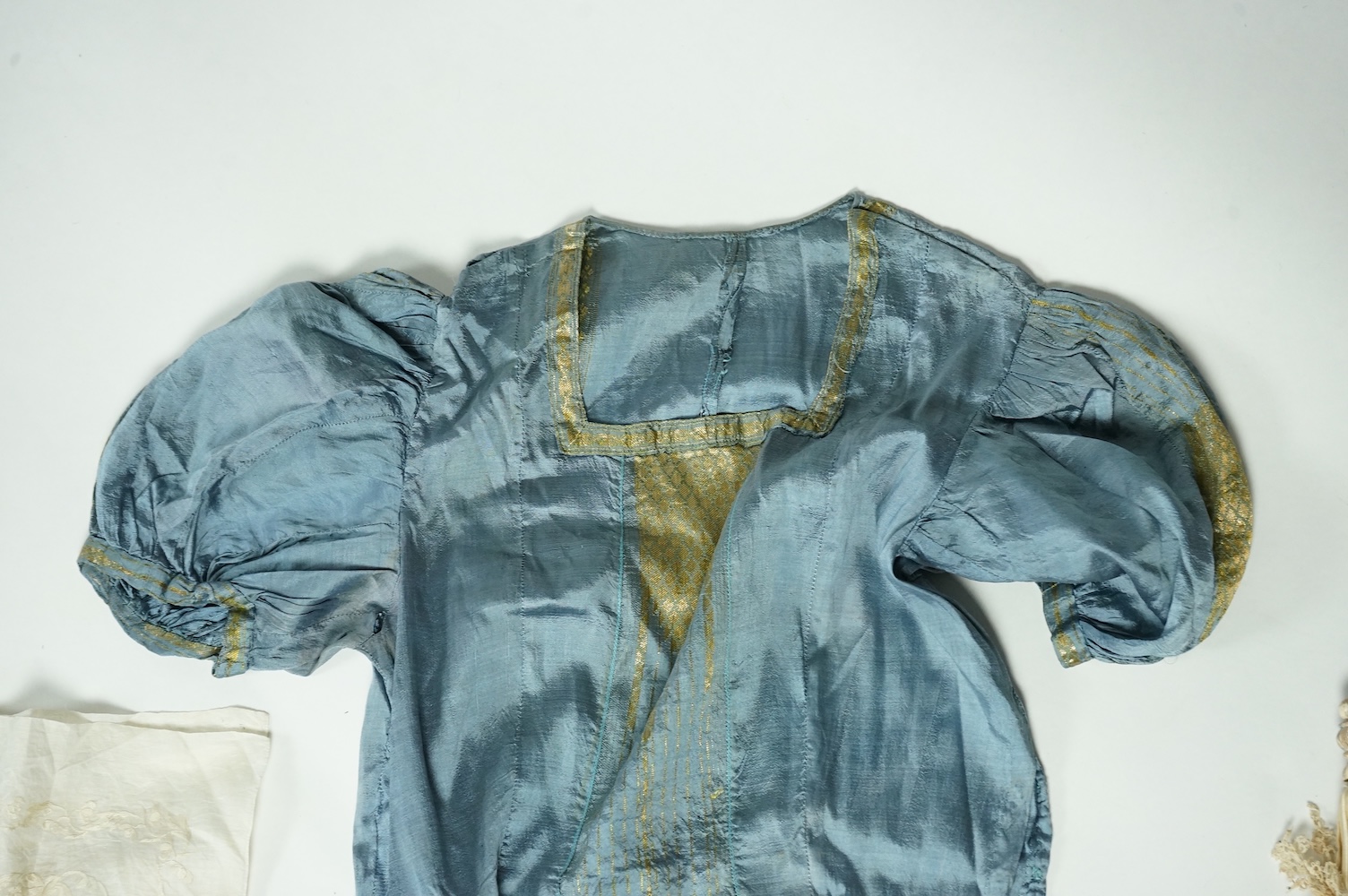 An early 19th century cream silk and metal thread embroidered ladies bonnet, an interesting 1930’s blue silk and gold thread dress fabric designed with Secessionist influences, an earlier fine linen silk embroidered kerc